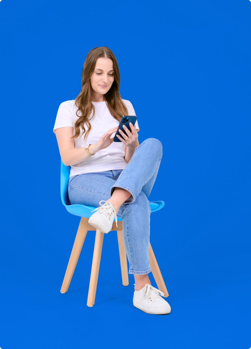 A young woman sitting on a chair and using a cell phone.