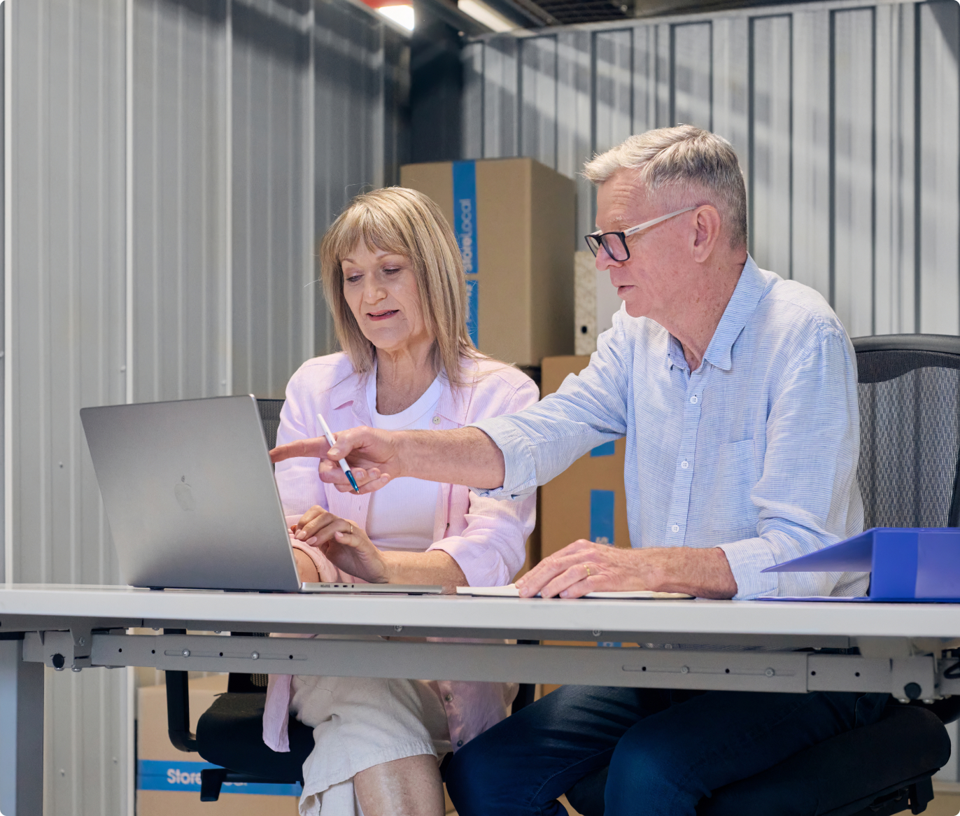 A man and woman looking at a laptop in a storage unit.
