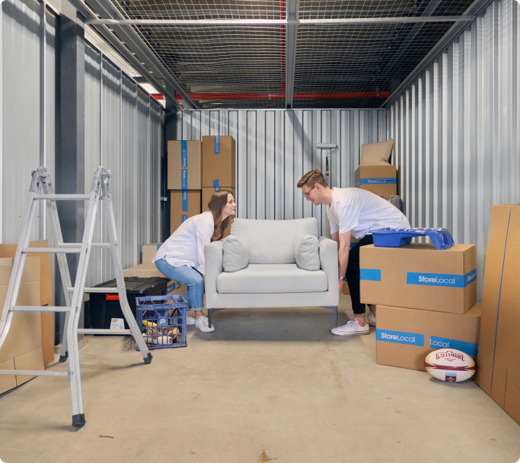 Two people moving a couch into a storage room.