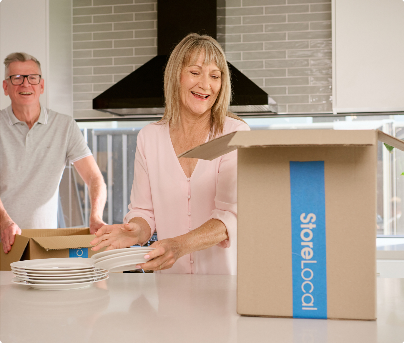 A man and woman opening a box in the kitchen.