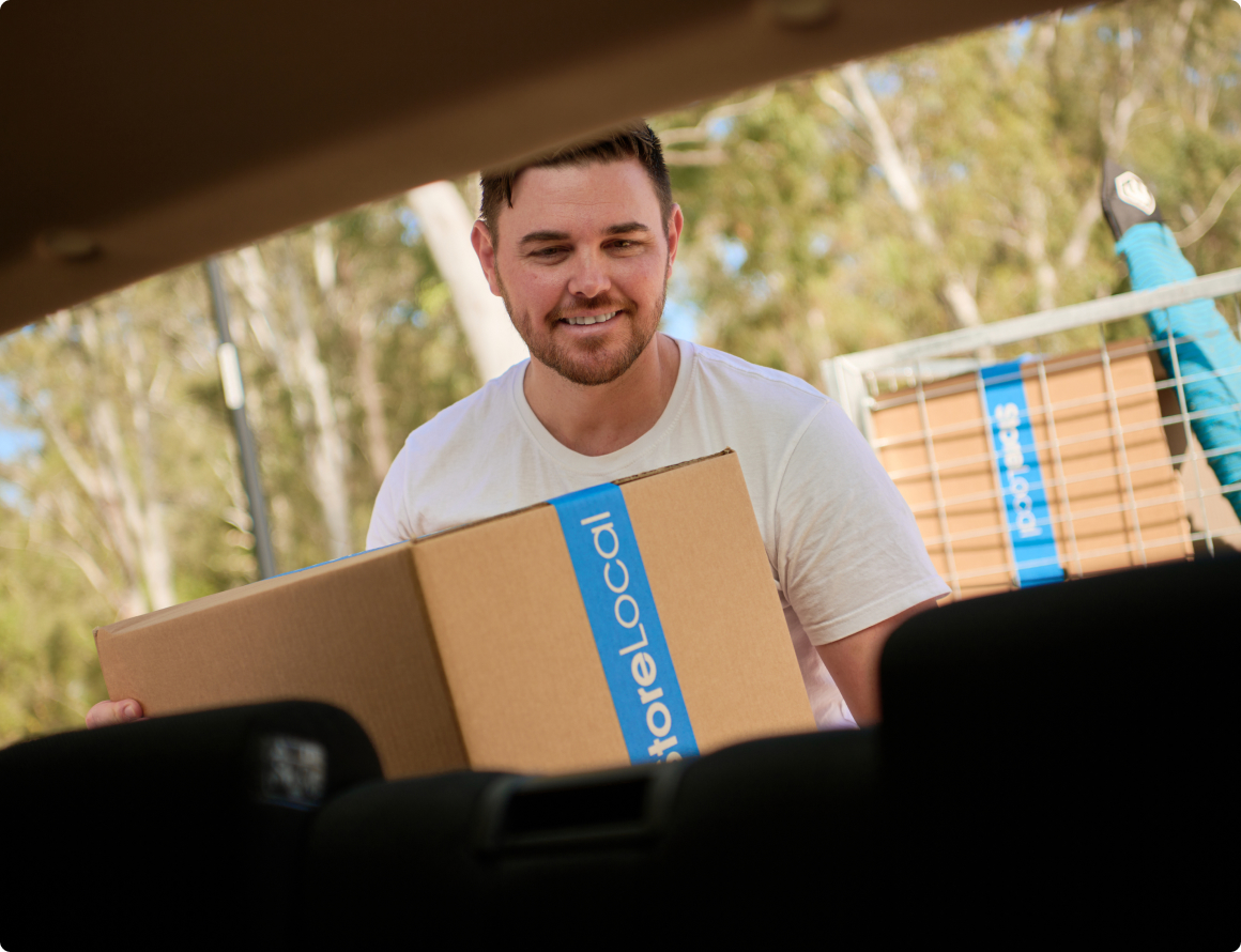 A man holding a box in the back seat of a car.