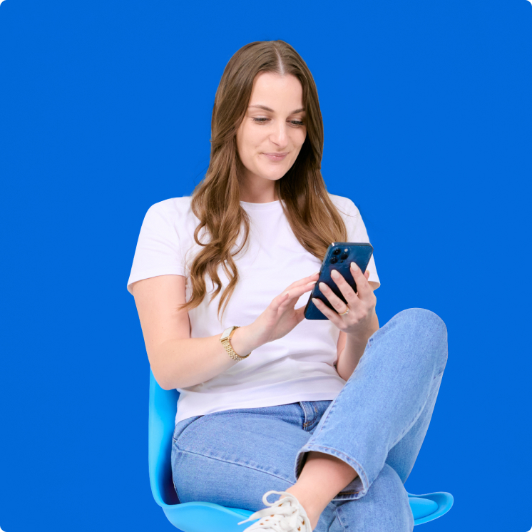 A woman sitting on a blue chair looking at her phone.